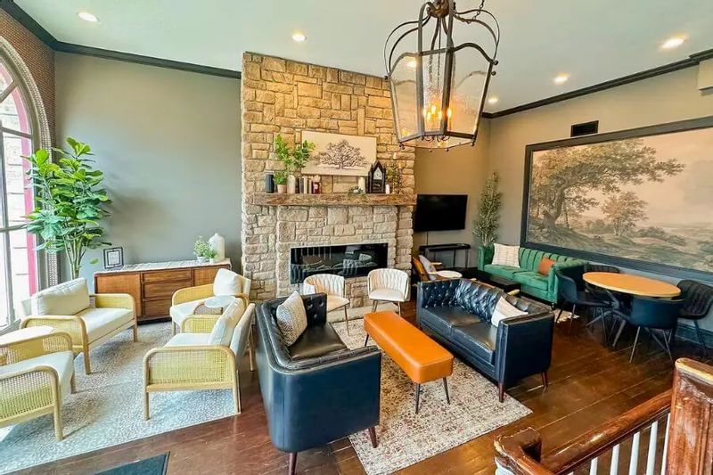 The lobby at Hotel Lanesboro featuring a stone fireplace, comfortable seating areas, wood floors, and warm lighting that create an inviting gathering space.